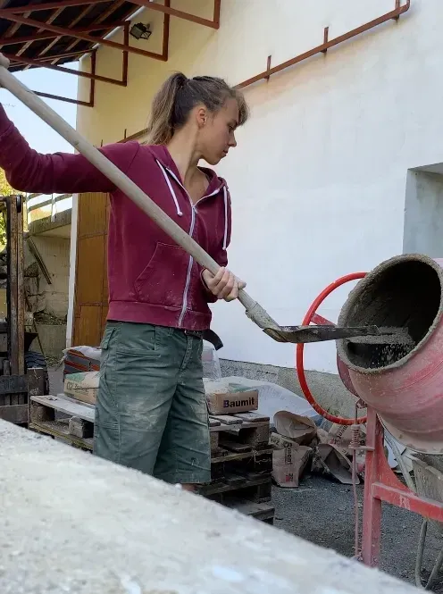Romi Netzberger schaufelt Sand in die Betonmischmaschine