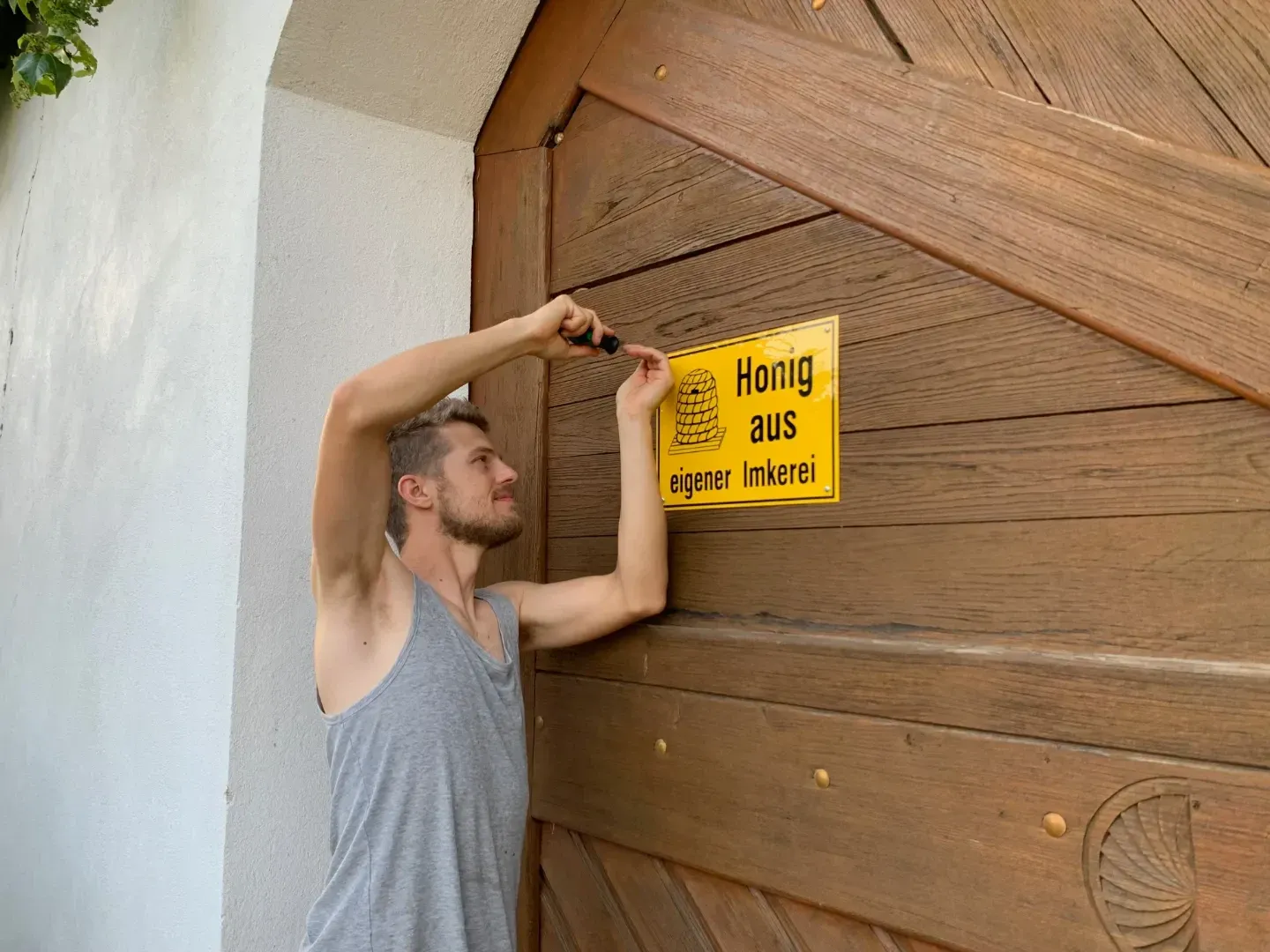 Matthias Amon montiert das Schild 'Honig aus eigener Imkerei'