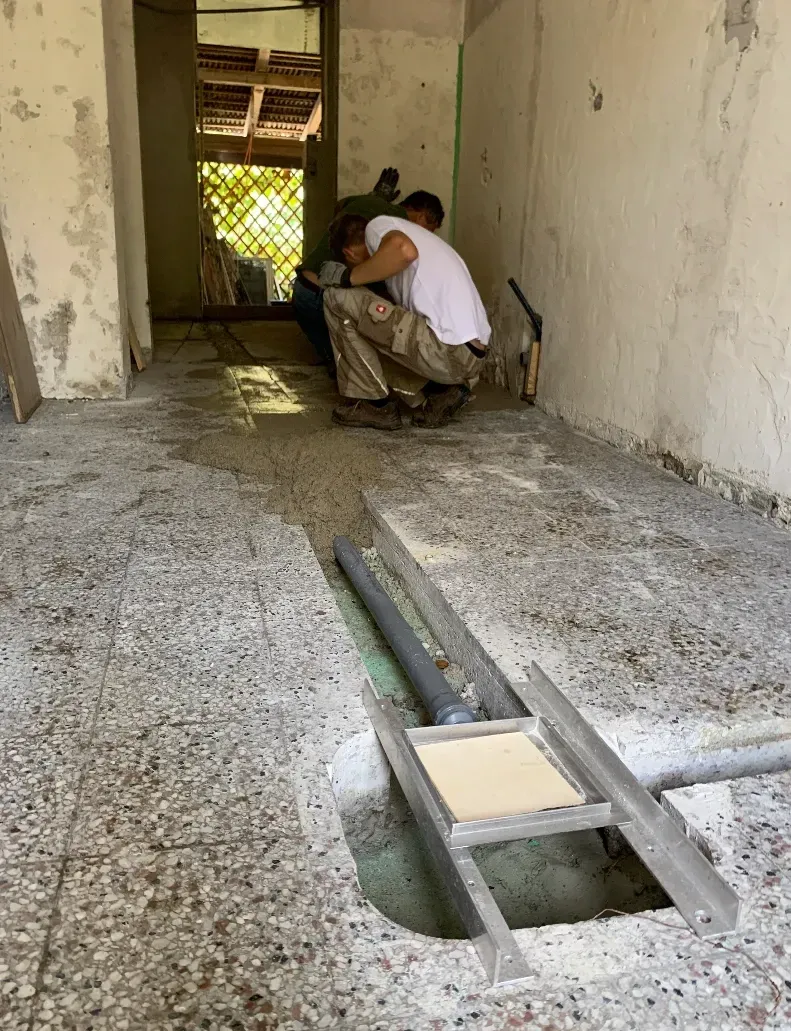 Im zukünftigen Honigverarbeitungsraum werden von Matthias und seinem Vater Wasserleitungen im Boden und in der Wand verlegt